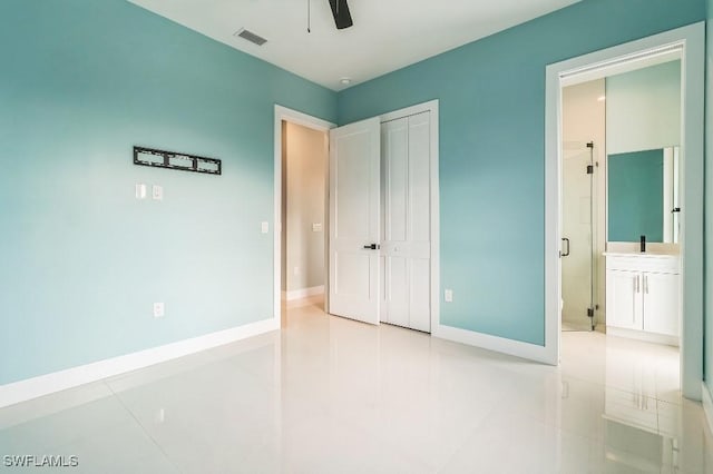 unfurnished bedroom with ceiling fan, ensuite bathroom, light tile patterned floors, and sink