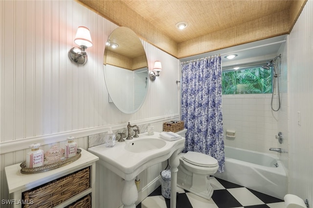 bathroom featuring toilet, shower / tub combo with curtain, and wooden walls