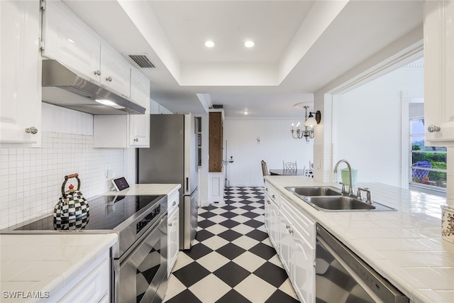 kitchen with tile counters, sink, backsplash, white cabinets, and appliances with stainless steel finishes