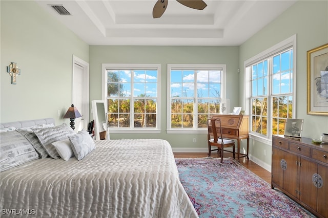 bedroom featuring hardwood / wood-style flooring, ceiling fan, and a raised ceiling