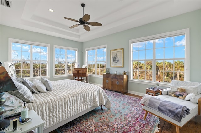 bedroom featuring hardwood / wood-style flooring, ceiling fan, and a raised ceiling