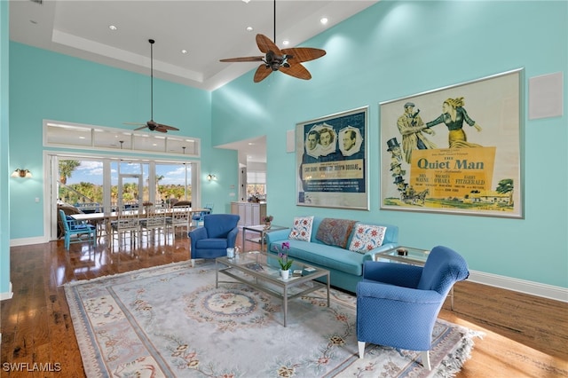 living room with a high ceiling, hardwood / wood-style floors, and ceiling fan