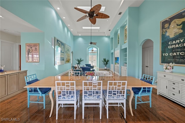 dining area featuring a towering ceiling, hardwood / wood-style flooring, and ceiling fan