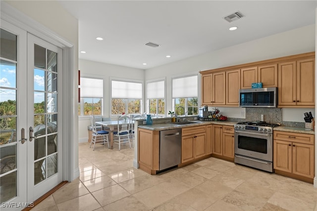 kitchen with french doors, light stone counters, backsplash, appliances with stainless steel finishes, and sink