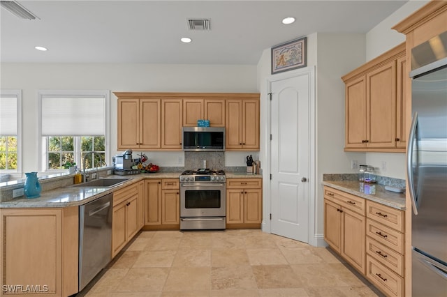 kitchen featuring light brown cabinetry, stainless steel appliances, sink, and light stone counters