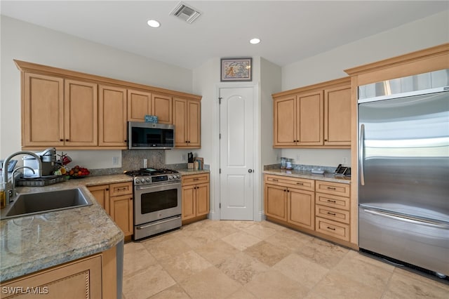 kitchen featuring appliances with stainless steel finishes, sink, and light stone counters