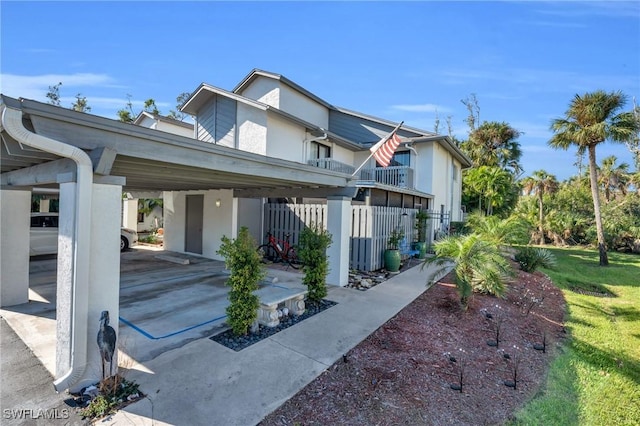 exterior space with a carport, a balcony, and a front lawn