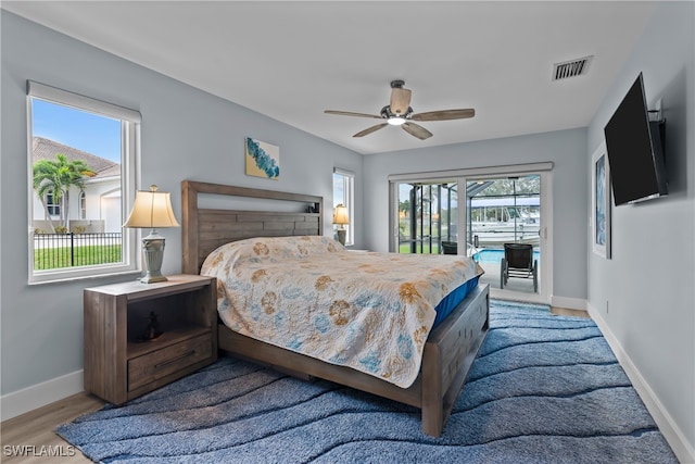 bedroom featuring multiple windows, ceiling fan, light hardwood / wood-style floors, and access to exterior