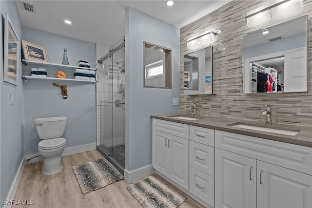 bathroom with hardwood / wood-style floors, vanity, backsplash, toilet, and a shower with shower door