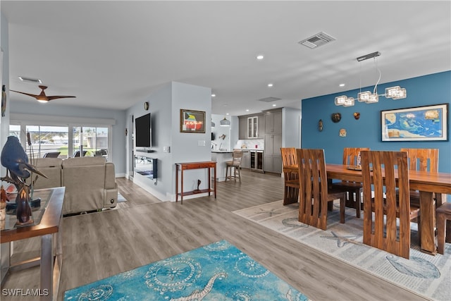 dining space featuring ceiling fan with notable chandelier and light hardwood / wood-style flooring