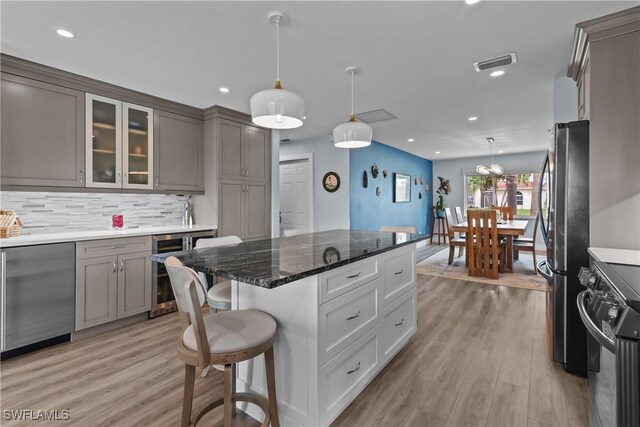 kitchen featuring gray cabinetry, stainless steel appliances, a kitchen breakfast bar, light hardwood / wood-style floors, and decorative light fixtures