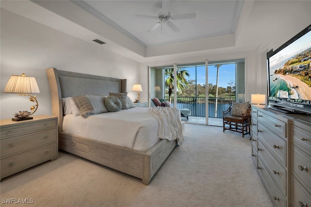 carpeted bedroom with ceiling fan, access to exterior, and a raised ceiling