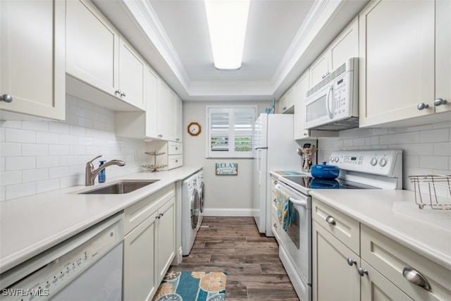 kitchen featuring dark hardwood / wood-style floors, white appliances, washing machine and dryer, white cabinets, and sink