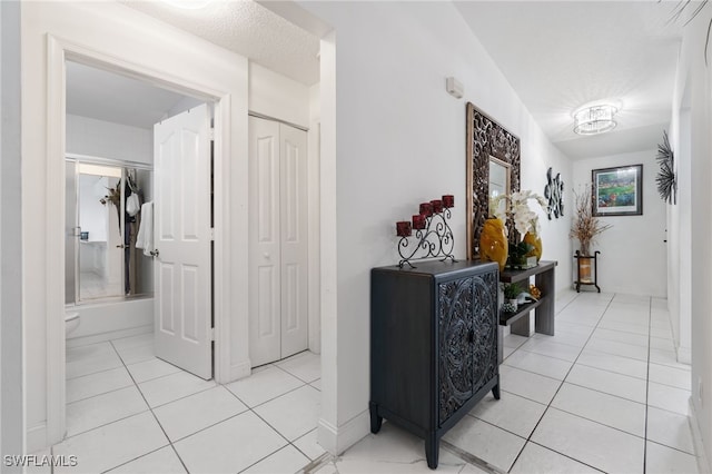 corridor with light tile patterned flooring and a textured ceiling