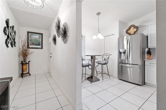 kitchen featuring a notable chandelier, light tile patterned flooring, white cabinetry, and stainless steel refrigerator with ice dispenser