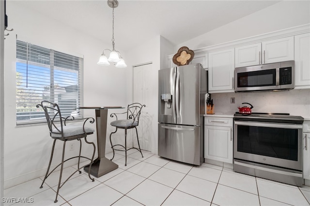 kitchen with stainless steel appliances, white cabinets, decorative light fixtures, vaulted ceiling, and light tile patterned flooring