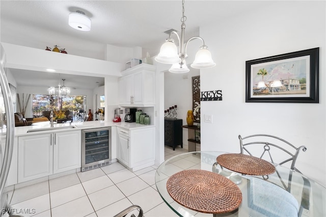 kitchen with wine cooler, white cabinetry, sink, and decorative light fixtures