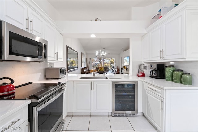 kitchen with appliances with stainless steel finishes, white cabinets, wine cooler, and vaulted ceiling