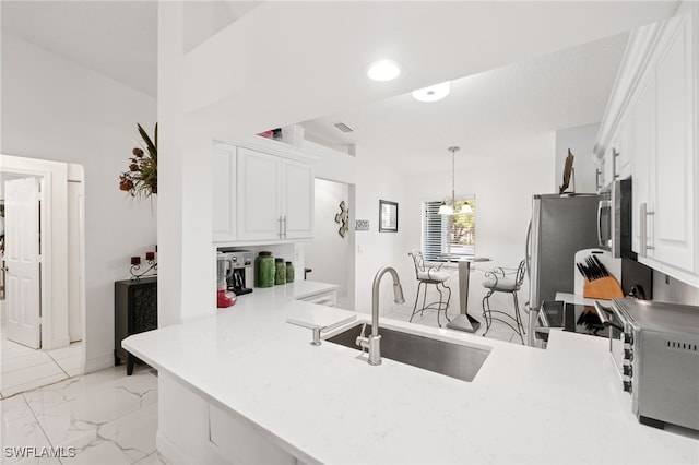 kitchen featuring pendant lighting, kitchen peninsula, sink, white cabinetry, and stainless steel appliances