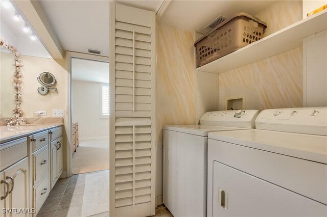 clothes washing area featuring washer and clothes dryer, light tile patterned floors, and sink