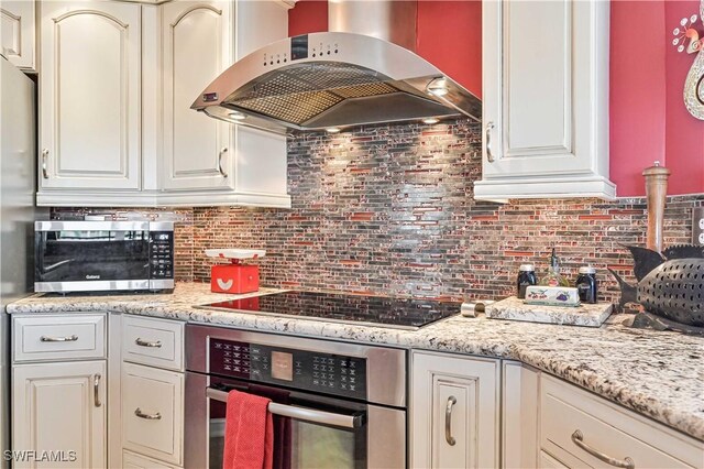 kitchen with backsplash, exhaust hood, and appliances with stainless steel finishes