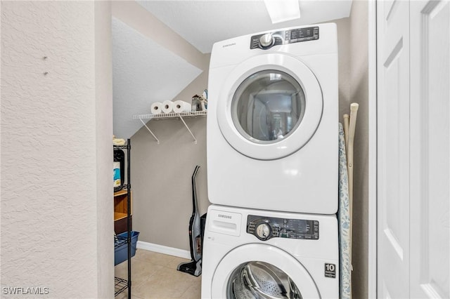 20111 Seagrove St Unit 604, Estero, FL 33928 - laundry room featuring stacked washer and clothes dryer, tile patterned flooring, baseboards, and a textured wall