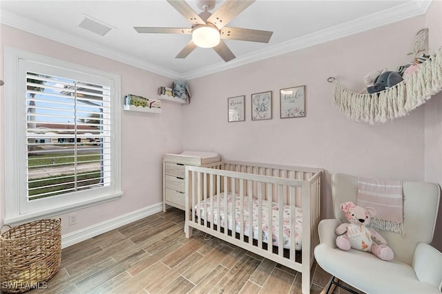 bedroom featuring ceiling fan, a crib, multiple windows, and ornamental molding