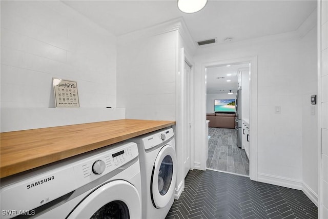 clothes washing area with ornamental molding and washing machine and clothes dryer