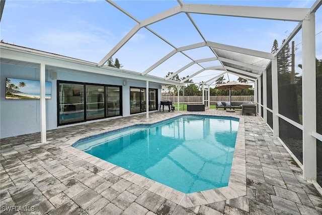 view of swimming pool with an outdoor living space, a patio area, and glass enclosure