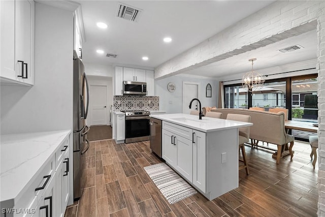 kitchen with appliances with stainless steel finishes, sink, white cabinetry, and a center island with sink