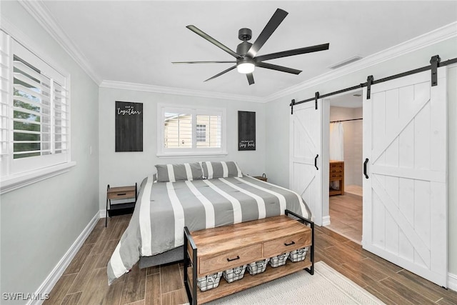 bedroom featuring ceiling fan, ornamental molding, and a barn door