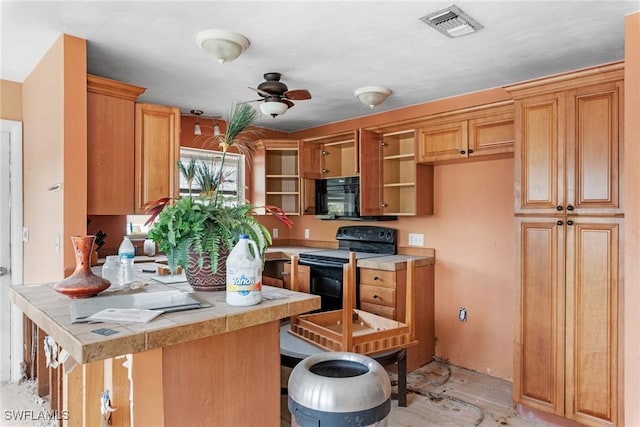 kitchen with black appliances, ceiling fan, and a kitchen bar