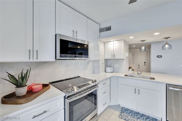 kitchen with backsplash, stainless steel appliances, sink, light tile patterned floors, and white cabinets