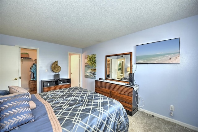 bedroom featuring carpet flooring, a closet, a textured ceiling, and a spacious closet