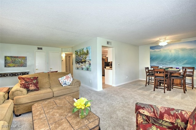 living room with ceiling fan, light colored carpet, and a textured ceiling