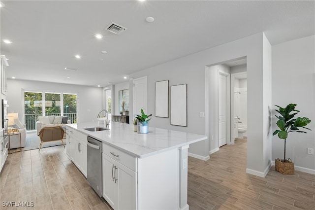 kitchen with white cabinets, light hardwood / wood-style flooring, a center island with sink, and sink