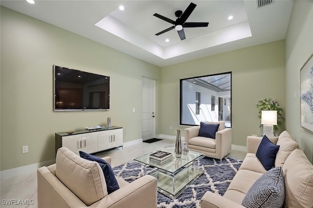 living room featuring ceiling fan and a tray ceiling