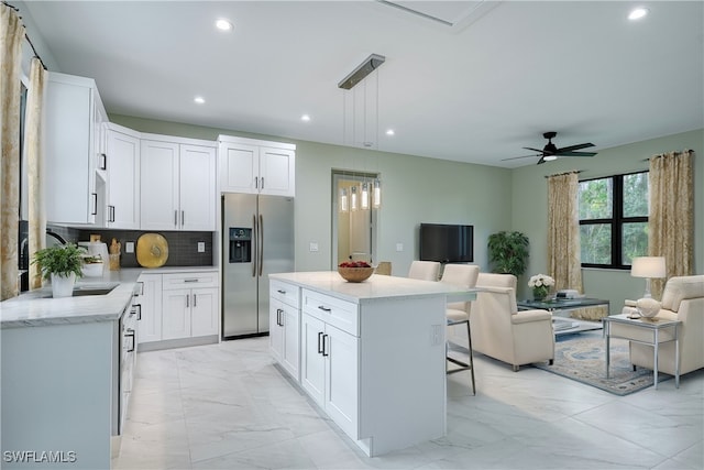 kitchen featuring white cabinetry, stainless steel fridge, a kitchen island, and pendant lighting