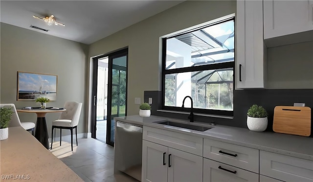 kitchen with white cabinetry, sink, light tile patterned flooring, and stainless steel dishwasher