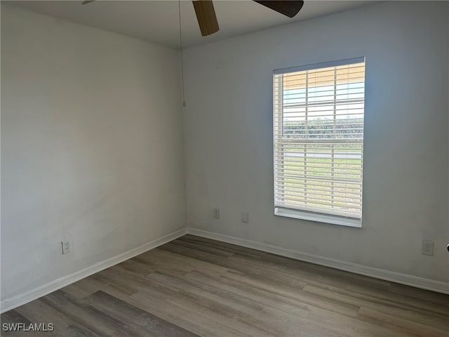 empty room with a wealth of natural light, wood-type flooring, and ceiling fan