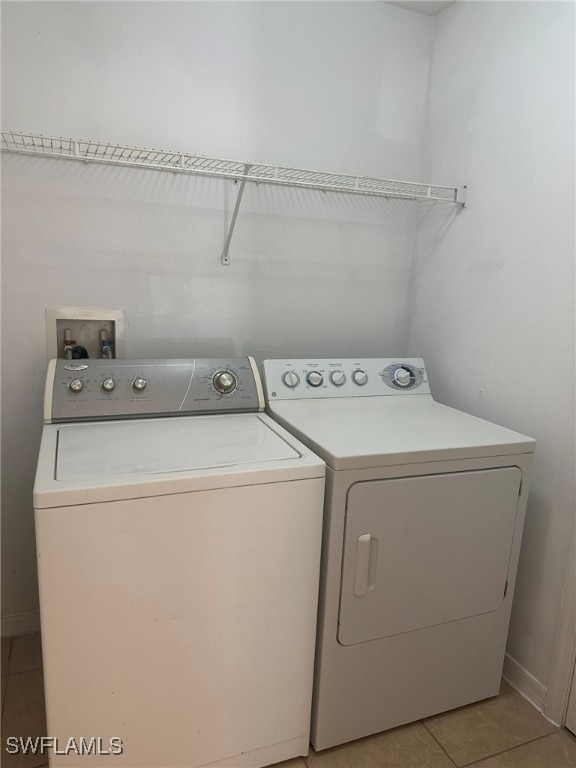 clothes washing area with light tile patterned flooring and independent washer and dryer