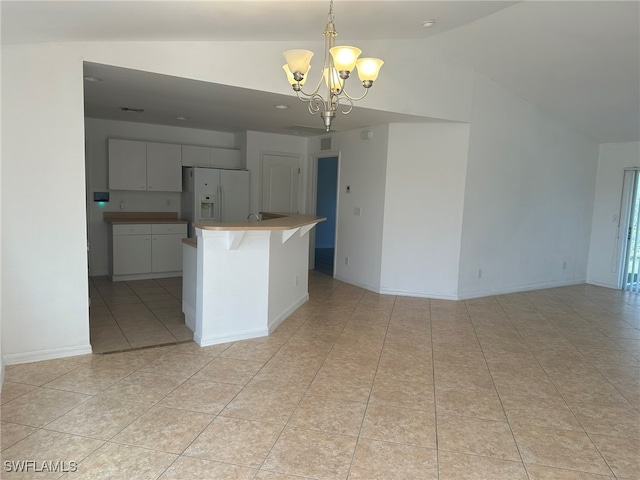 kitchen featuring light tile patterned flooring, white fridge with ice dispenser, hanging light fixtures, lofted ceiling, and a notable chandelier