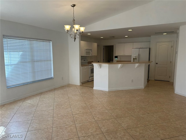 kitchen featuring a kitchen bar, white appliances, a chandelier, lofted ceiling, and pendant lighting