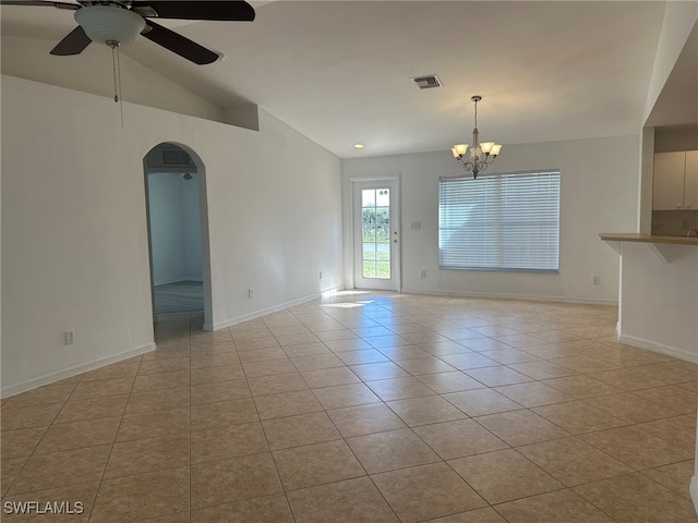 empty room featuring light tile patterned flooring, ceiling fan with notable chandelier, and lofted ceiling