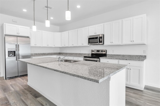 kitchen with light wood-type flooring, stainless steel appliances, sink, white cabinetry, and an island with sink