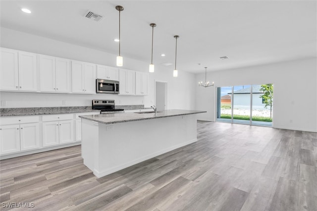 kitchen featuring appliances with stainless steel finishes, light wood-type flooring, a kitchen island with sink, white cabinetry, and hanging light fixtures