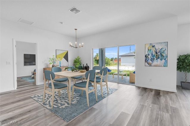 dining room with light hardwood / wood-style flooring and a notable chandelier