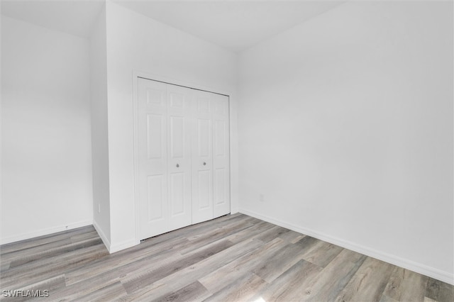 unfurnished bedroom with light hardwood / wood-style floors and a closet