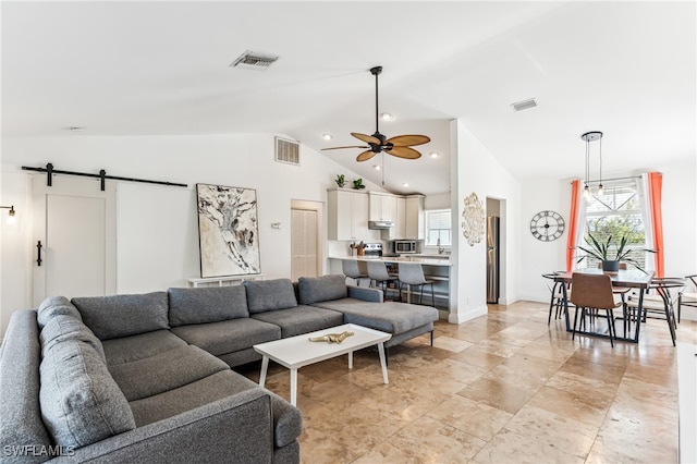 living room featuring a barn door, ceiling fan, and vaulted ceiling