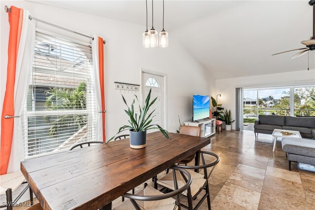 dining room featuring high vaulted ceiling and ceiling fan with notable chandelier